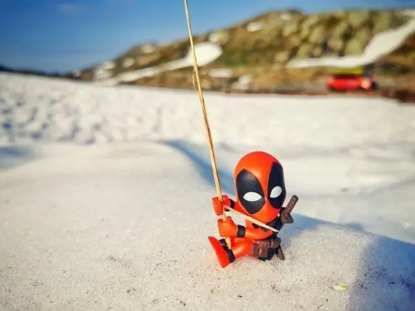 Figur sitzt im Schnee und hält eine Angelrute in der Hand