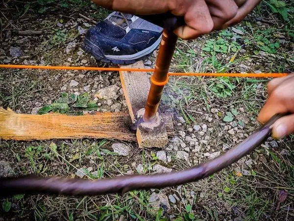 Holzstück mit Bohrer erzeugt Rauch beim Feuermachen