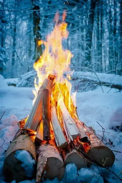 Kleine Flamme brennt auf einem Holzstapel im Schnee