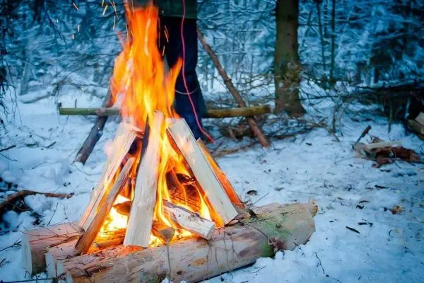 Kleine Flamme brennt auf einem Holzstapel im Schnee