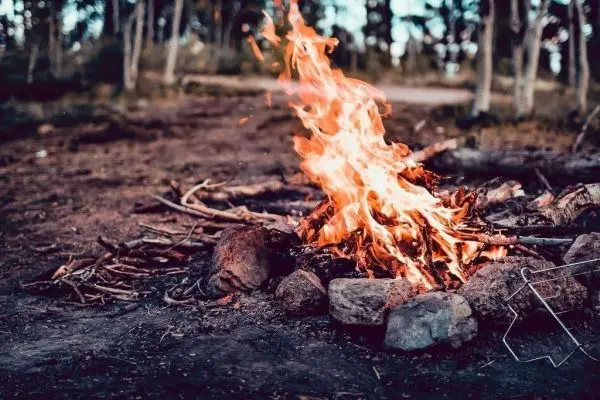 Kleine Flamme brennt zwischen Steinen auf dem Boden