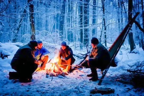 Kleine Flamme wärmt Gruppe in verschneiter Waldlandschaft