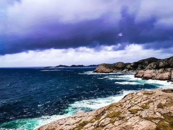 Küstenlandschaft mit Wellen, Felsen und bewölktem Himmel
