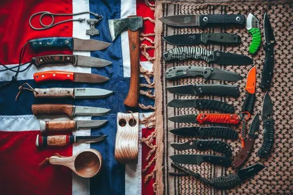 Verschiedene Messer und eine Axt auf einem Tuch mit Mustern und Farben