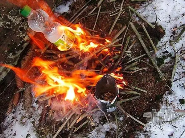 Kleine Flamme brennt auf einem Haufen Zweige neben einer Dose