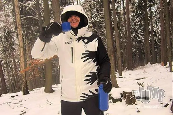 Person hält eine blaue Wasserflasche in einem verschneiten Wald