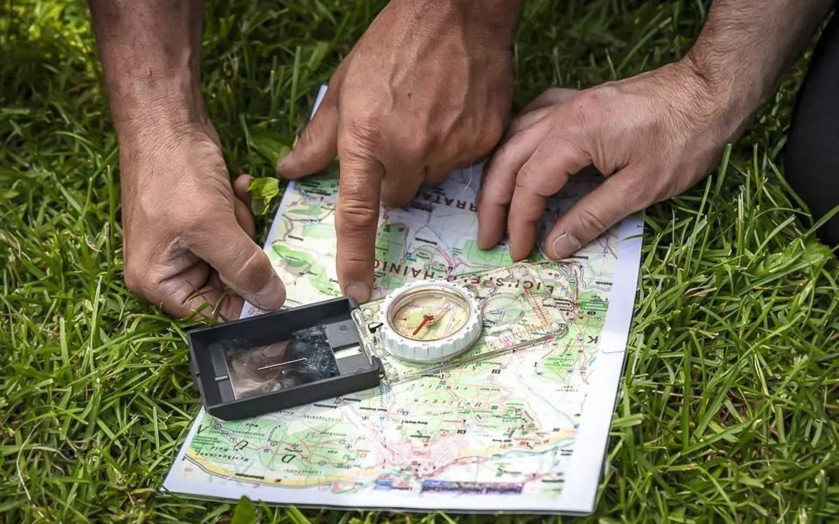Plattenkompass liegt auf einer topografischen Karte; Hilfslinien der Kompasskapsel sind parallel zum Kartengitter ausgerichtet