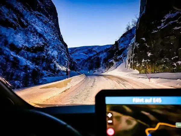 Blick auf eine schneebedeckte Straße zwischen hohen Felsen bei Dämmerung