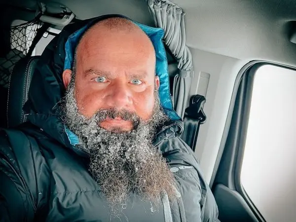 Mann mit gefrorenem Bart und blauen Augen im Fahrzeug