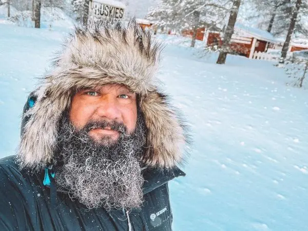 Mann mit Pelzmütze und dicker Jacke steht im Schnee