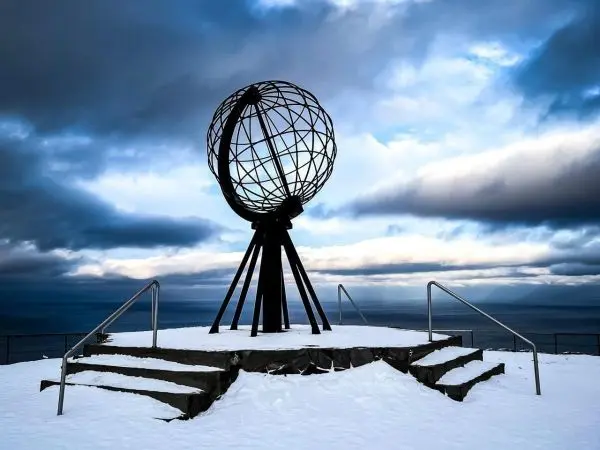 Metallglobus auf einer Plattform aus Stein, umgeben von Schnee und Wolken