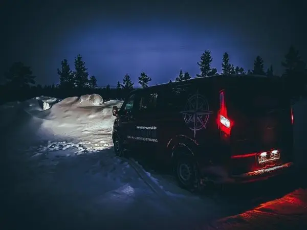 Rotes Fahrzeug steht auf verschneiter Fläche bei Nacht