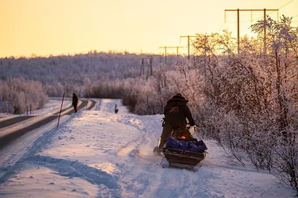 Schlitten wird auf verschneitem Weg gezogen, umgeben von winterlicher Landschaft