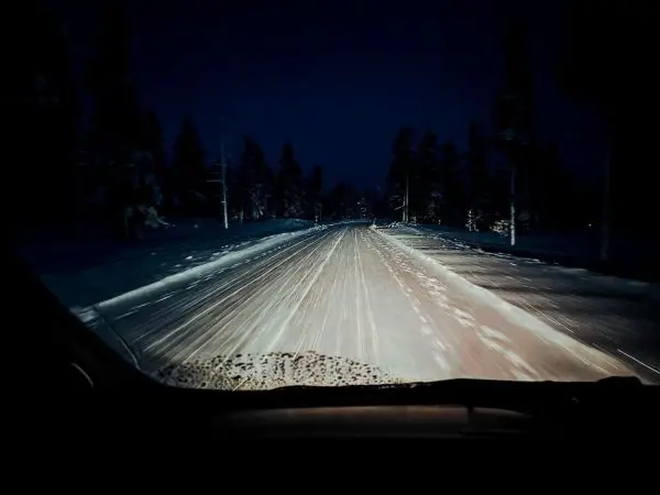Schneebedeckte Straße bei Nacht mit Lichtstrahlen von Fahrzeugen