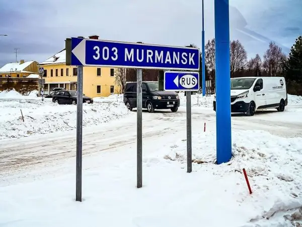 Wegweiser nach Murmansk, Schnee, Fahrzeuge im Hintergrund
