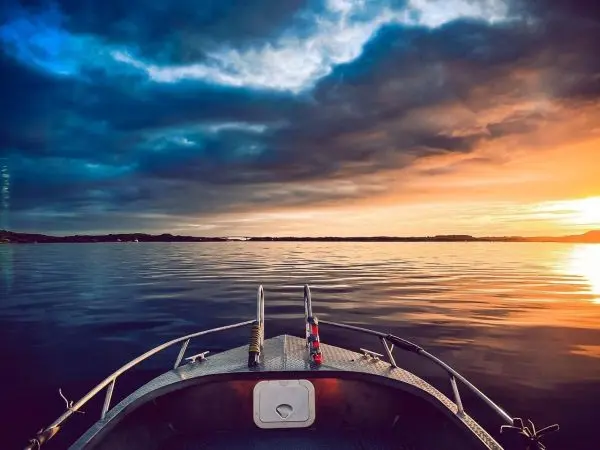 Blick von einem Boot auf einen ruhigen See bei Sonnenuntergang