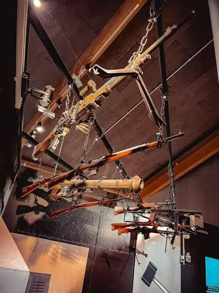 Eine Reihe von Gewehren hängt an Ketten von der Decke