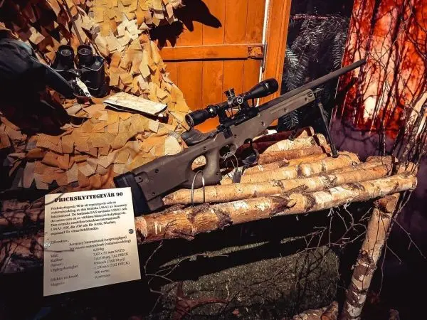 Gewehr mit Zielfernrohr auf einem Holzgestell aus Ästen und Rinde platziert