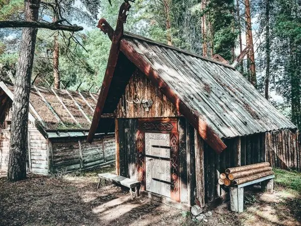 Holzhütte mit geschnitztem Dach und Holzbank vor der Tür im Wald