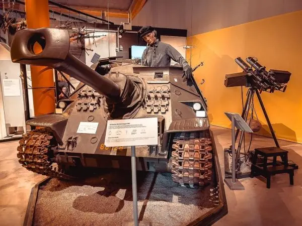 Panzer mit aufgesetztem Geschütz in einer Ausstellung, daneben weitere militärische Ausrüstung