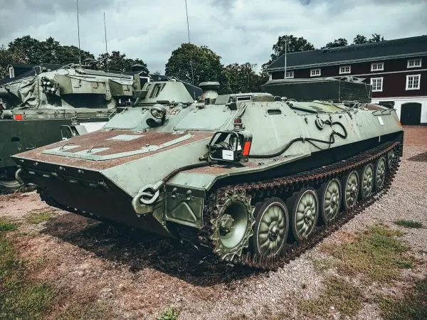 Panzerfahrzeug auf einem Schotterplatz, im Hintergrund Gebäude