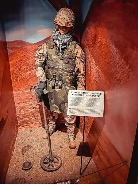 Soldat mit Minensuchgerät in militärischer Ausrüstung steht in Vitrine