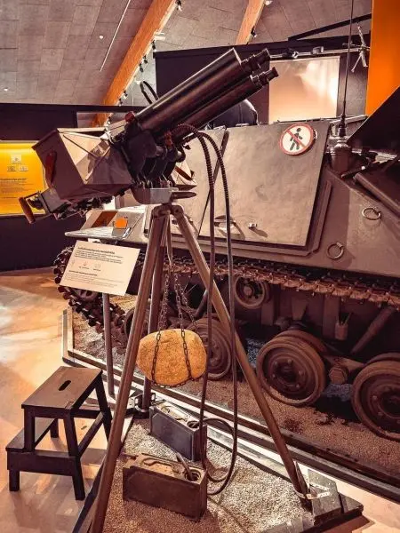 Stativ mit Geschütz und Gewicht, daneben ein Schild mit Informationen