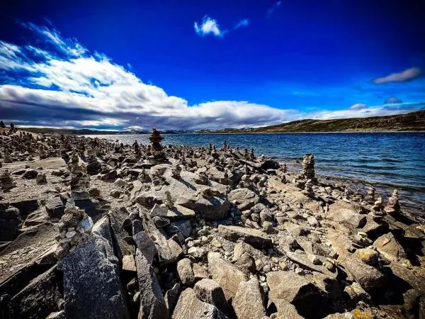 Steinmännchen stehen auf einer felsigen Uferlandschaft am Wasser
