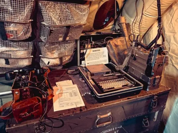 Tisch mit Schreibmaschine, Dokumenten und Kommunikationsgeräten in einem Zelt