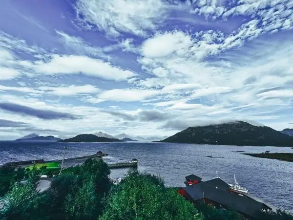 Blick auf ruhiges Wasser mit Bergen und Wolken im Hintergrund
