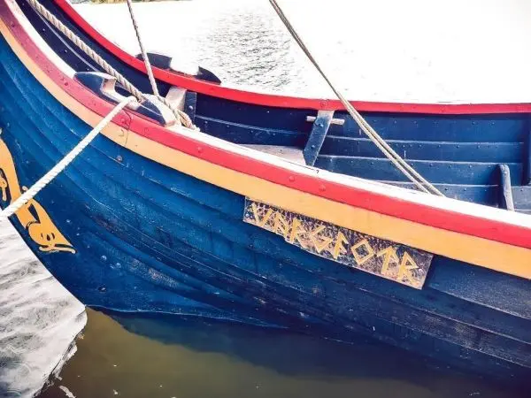 Bunte Holzbootseite mit Schriftzug und Seil am Rand