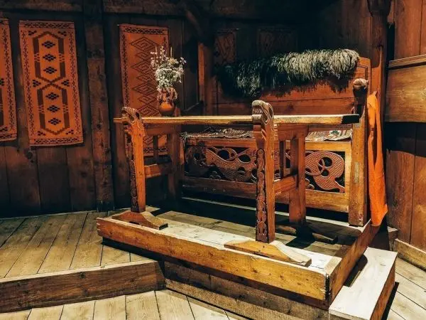 Holzbank mit kunstvollen Schnitzereien und einem Fell auf der Sitzfläche