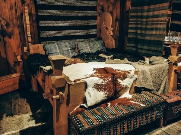 Holzbett mit Decken und Fellen, umgeben von Holzverkleidung und Textilien