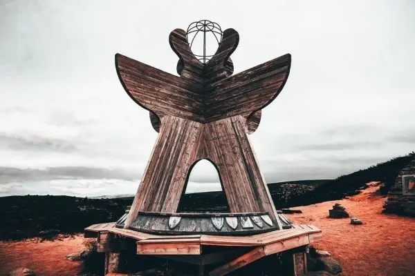 Holzkonstruktion mit symmetrischem Design und offenen Durchgängen auf sandigem Boden