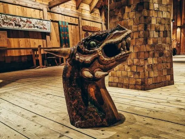 Holzskulptur eines Drachenkopfes steht auf dem Boden in einem Holzgebäude