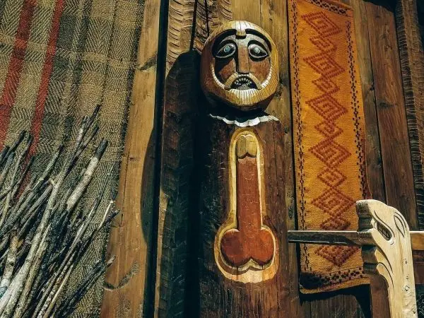 Holzskulptur mit Gesicht und geometrischen Mustern an der Wand