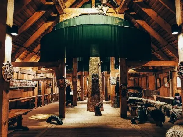 Holzstruktur mit Säulen, Decke und dekorativen Masken in einem Innenraum