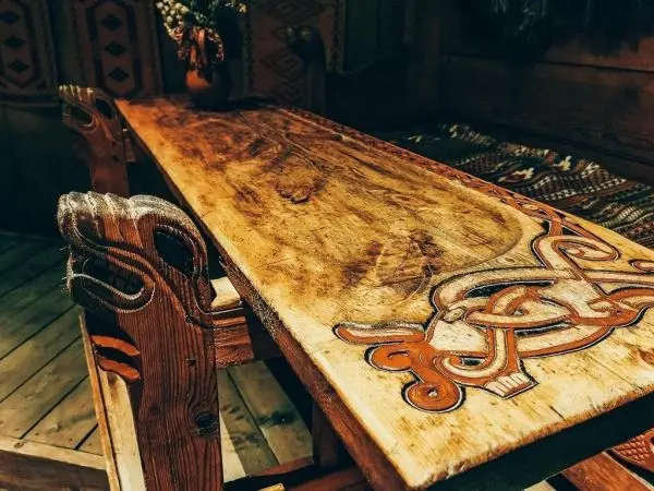Holztisch mit kunstvollen Schnitzereien und bemalten Verzierungen