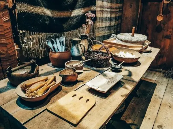 Holztisch mit verschiedenen Töpfen, Geschirr und Küchenutensilien in rustikalem Ambiente