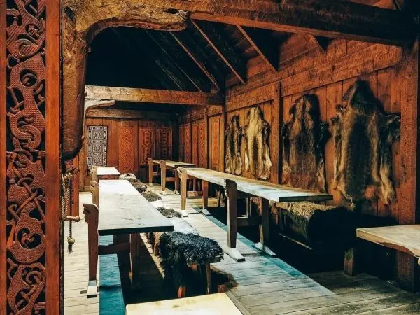Holzverkleideter Raum mit langen Tischen und Tierfellen an den Wänden