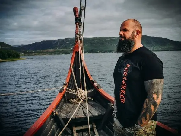 Mann steht an Bord eines Bootes mit Seil und Ruder im Hintergrund