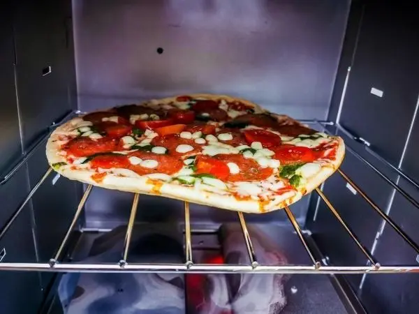 Pizza liegt auf einem Gitterrost in einem Ofen