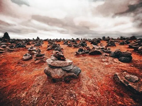 Steinansammlungen auf rotem Boden unter bewölktem Himmel