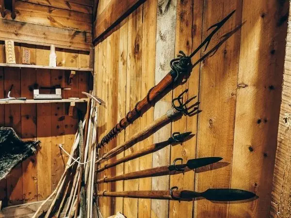 Wand mit verschiedenen Holzwerkzeugen und Speeren in einer rustikalen Umgebung