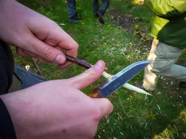 Ein Messer schnitzt einen Holzstock in der Natur