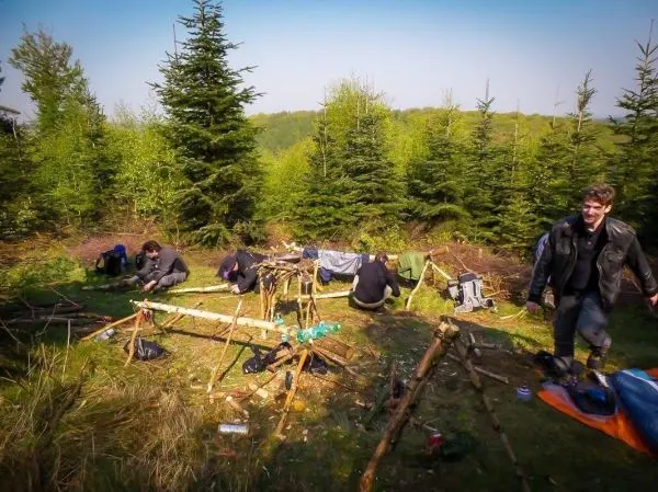 Gruppe arbeitet an einer selbstgebauten Konstruktion aus Ästen im Wald