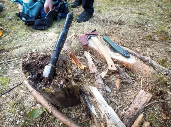 Axt und Messer liegen neben einem Holzstück mit einem Metallgegenstand