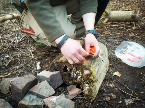 Feuerstahl erzeugt Funken auf Zunder auf einem Holzstück