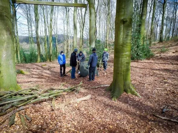 Gruppe arbeitet an einer Tarp-Notunterkunft zwischen Bäumen im Wald