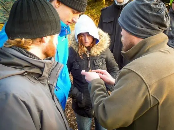 Gruppe betrachtet gemeinsam ein kleines Objekt in der Hand eines Teilnehmers